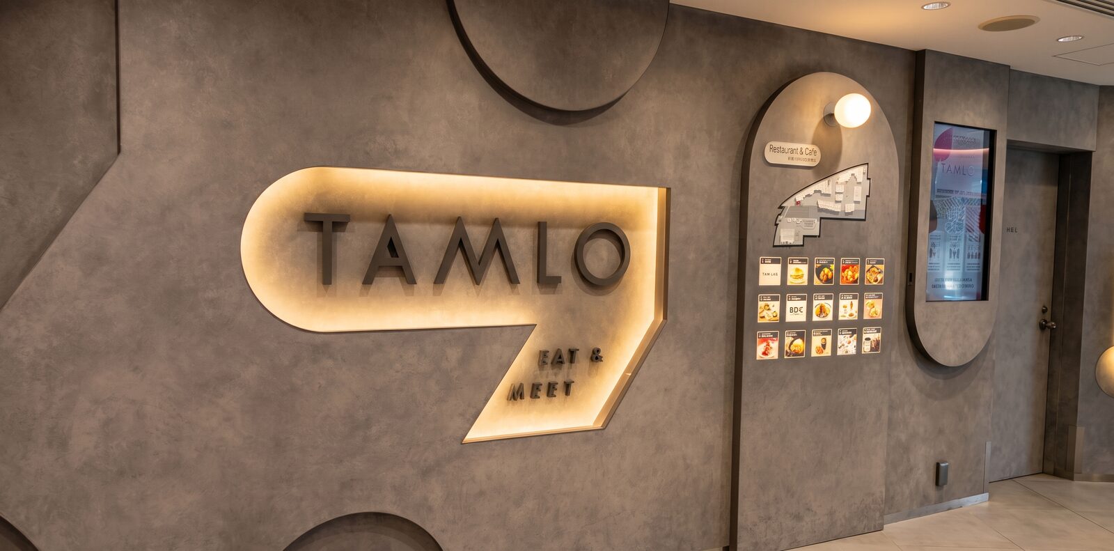 Illuminated TAMLO Eat and Meet Sign beside the Restaurant and Cafe Directory Board